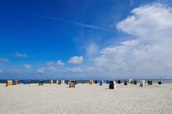 Strandkörbe am Sandstrand von Neßmersiel bei blauem Himmel und Sonnenschein
