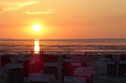 Sonnenuntergang hinter Strandkoerben am Strand von Bensersiel